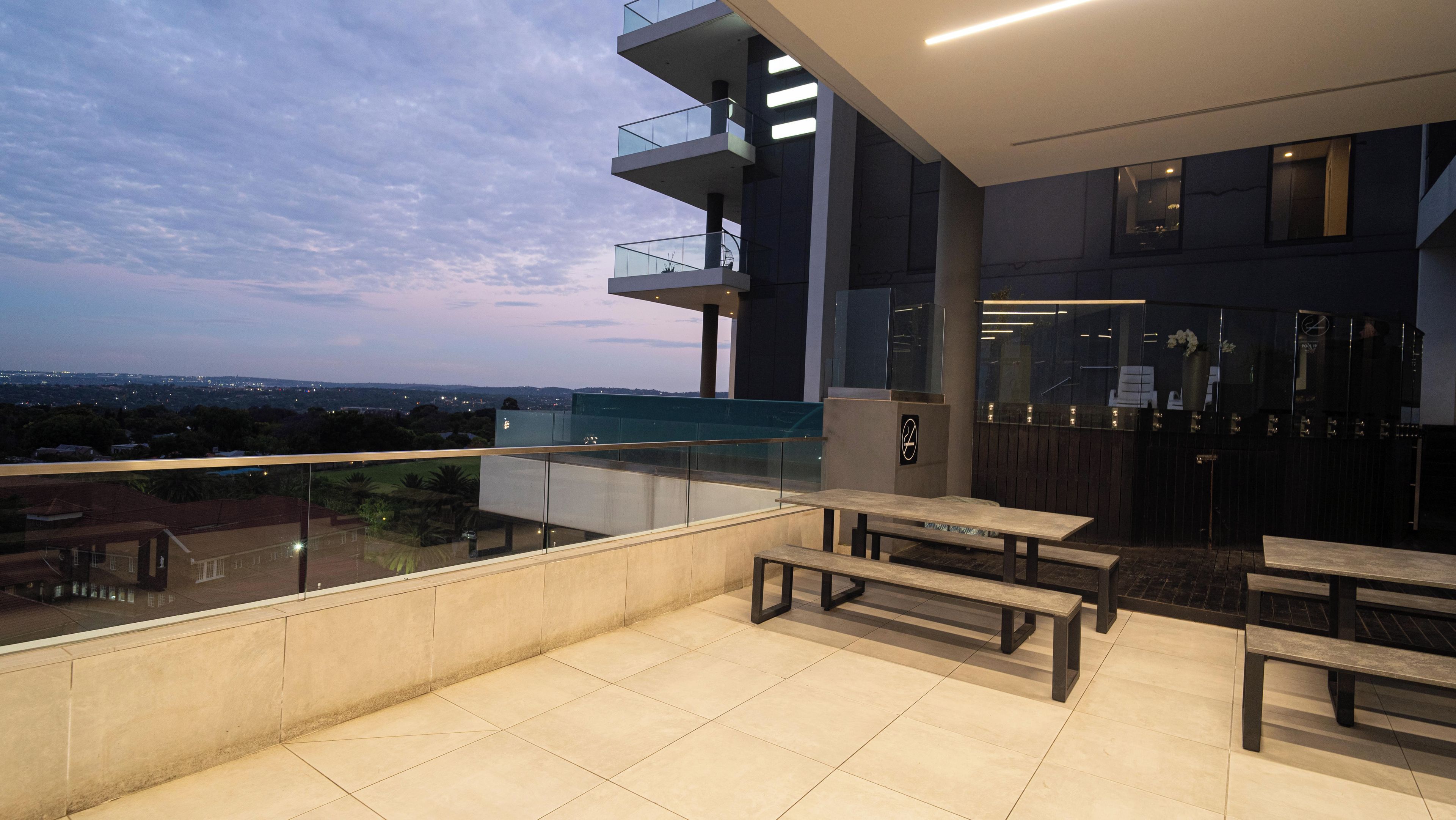 A modern outdoor terrace with a view of the cityscape at dusk.