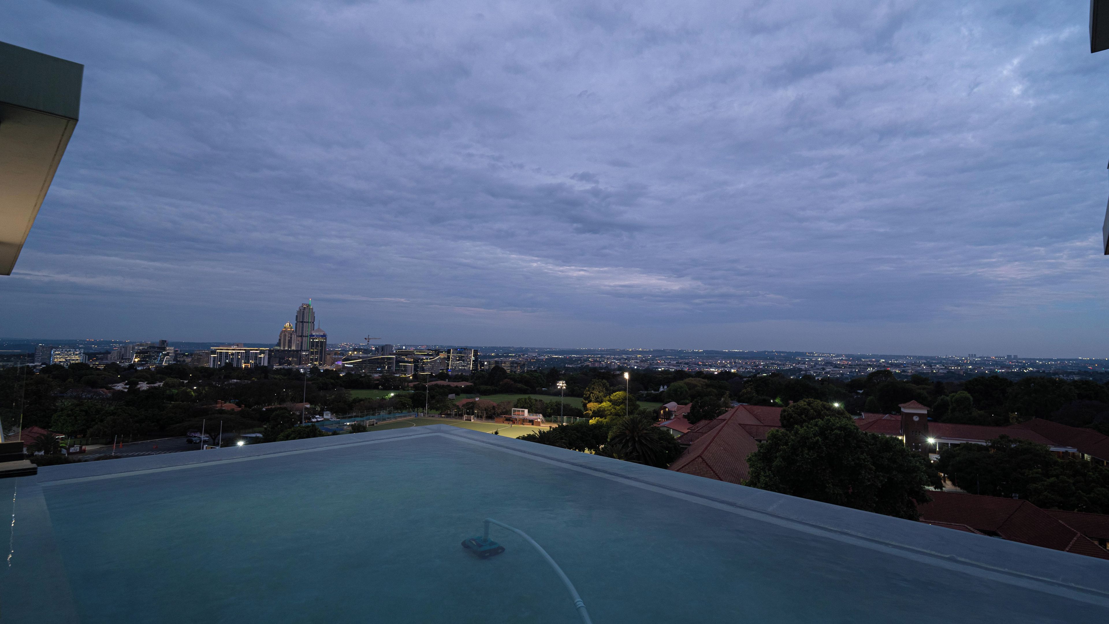 A rooftop pool with a view of a city skyline at dusk.
