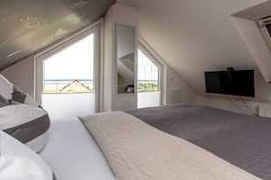 Ein Schlafzimmer mit einem Bett, einem Fernseher und Blick ins Freie.