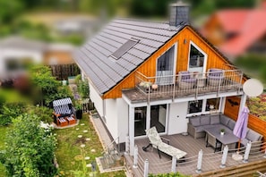 Ein zweistöckiges Haus mit Balkon, Terrasse und Garten.