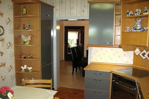 A kitchen with a stove, a sink, and a wooden cabinet with decorative items. - Holiday home in Detern with swimming pool (Detern)
