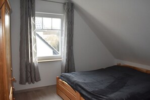 A bedroom with a single bed, a window with curtains, and a wooden wardrobe. - Holiday home in Breege with swimming pool (Breege)