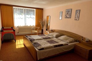 A hotel room with a bed, a chair, a dresser, a window with curtains, and wall art. - Valahof fattening barn (Milevsko)