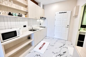 A modern kitchen with white cabinetry, a microwave, a sink, and a welcome mat. - Near Beach Condo With Pool Access in Pattaya City (Pattaya)
