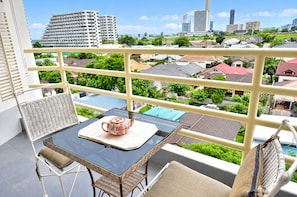 A balcony with a table, chairs, and a view of a cityscape. - Near Beach Condo With Pool Access in Pattaya City (Pattaya)