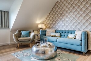 A living room with a blue sofa, a round coffee table, and a patterned rug. - Holiday apartment in List with swimming pool (List)