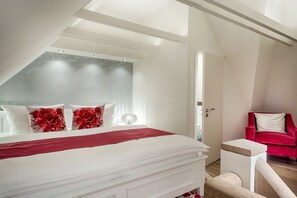 A bedroom with a bed, a red chair, and a white bedside table. - Holiday apartment in List with swimming pool (List)