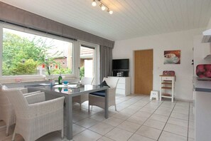 Ein modernes Wohnzimmer mit Essbereich, Fernseher und Küchenzeile.