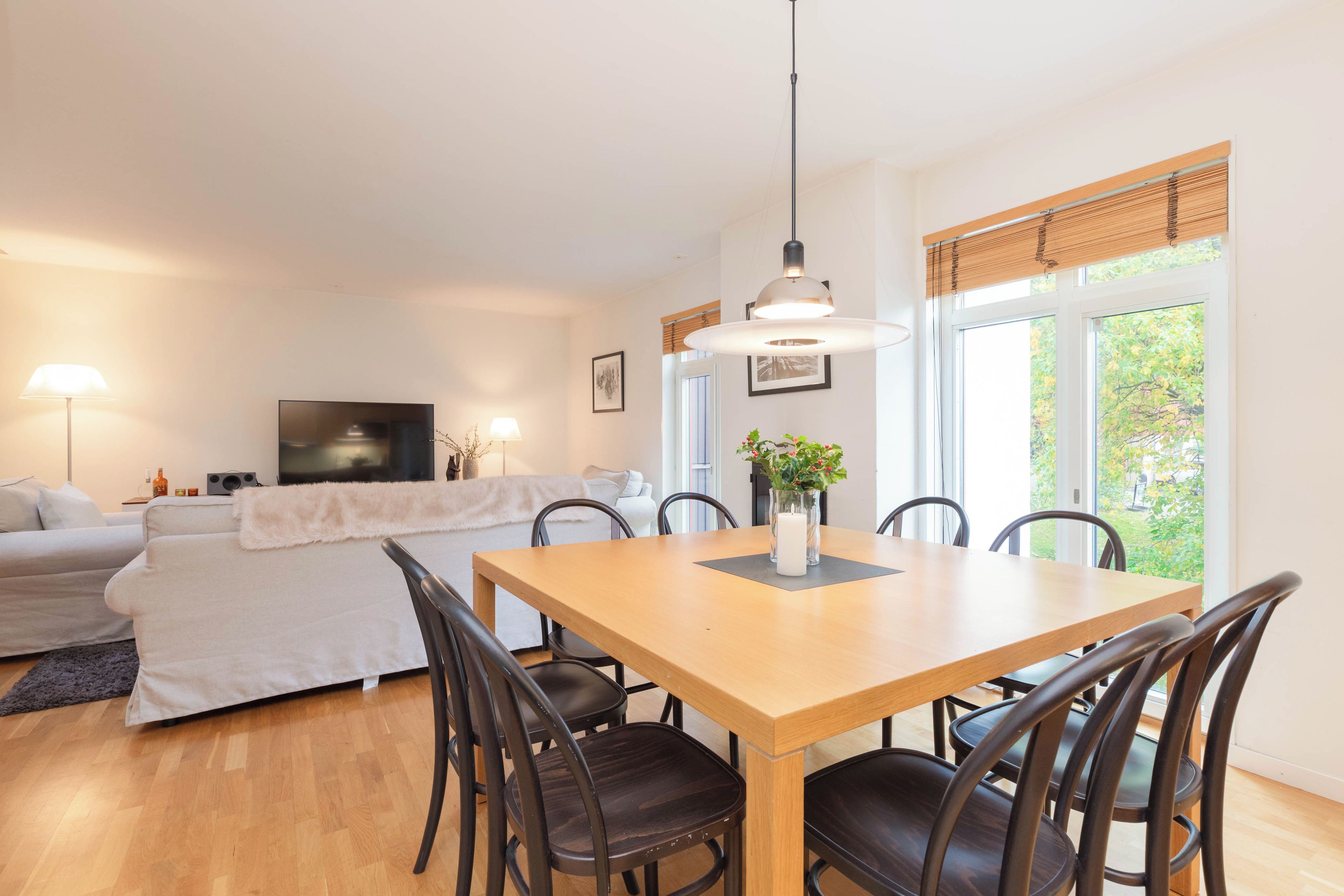 A modern living room with a sofa, a TV, and a dining area with a table and chairs.