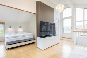 Ein modernes Schlafzimmer mit einem Bett, einem an der Wand montierten Fernseher und einem großen Fenster.