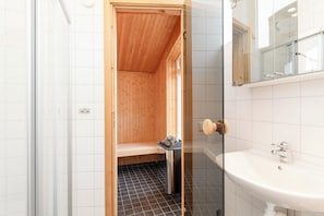 Ein kleines, kompaktes Badezimmer mit einer Holz-Duschrückwand, einem Waschbecken und einem Spiegel.