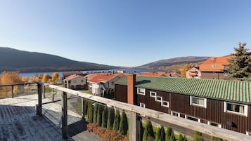 Un barrio residencial con una terraza de madera que da a un lago y colinas.