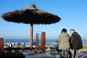 A wooden structure with a thatched roof overlooking a beach. - Norderney Sun Decks Apt. 11 (Norderney)