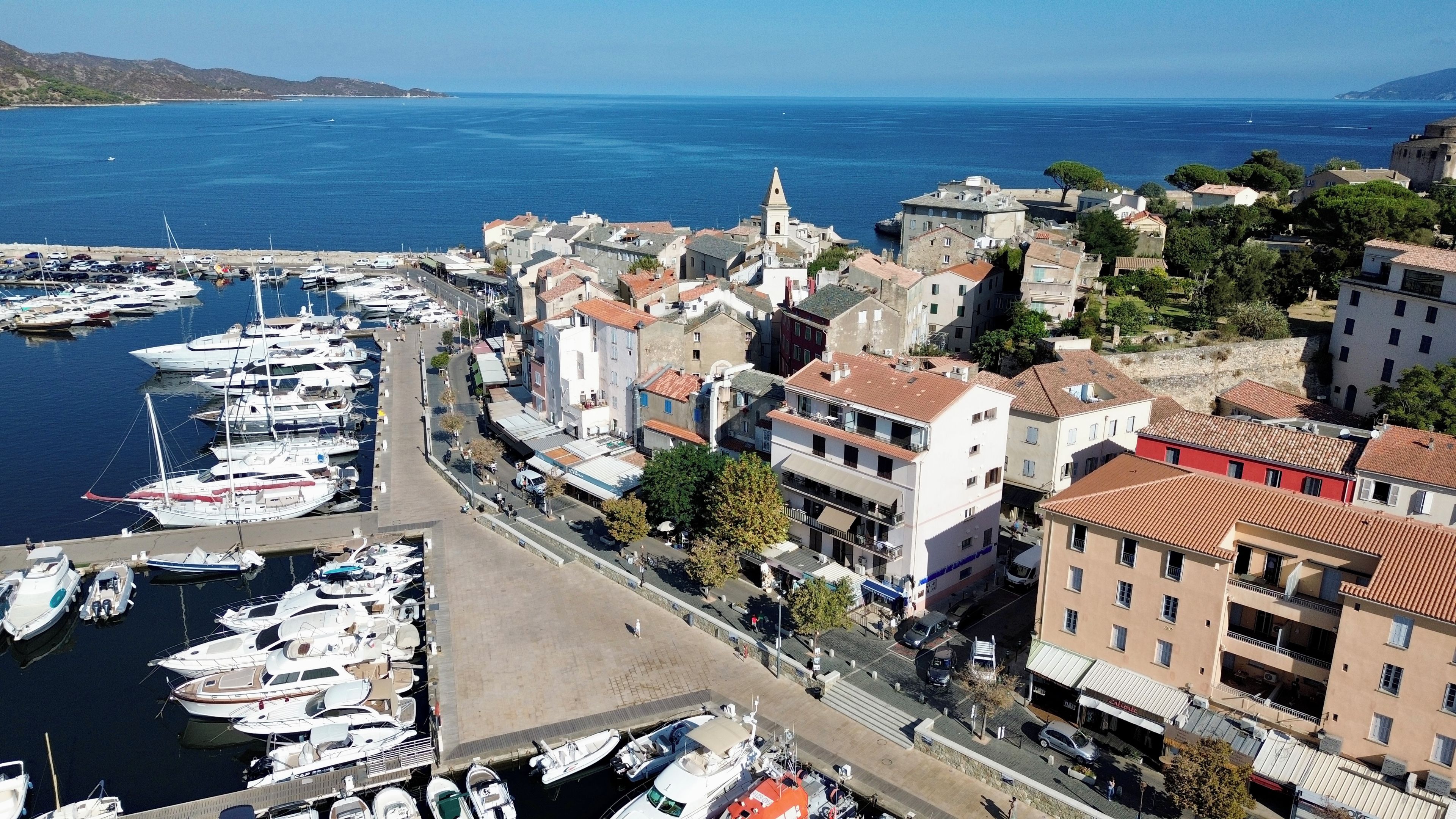 Un pueblo costero con un puerto deportivo, edificios históricos y una iglesia destacada.