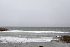 A beach with waves, a cloudy sky, and sparse vegetation. - HausamMeerbittesehr de (Klausdorf)