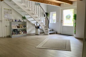 Ein geräumiger Raum mit einer Holztreppe, einem Bücherregal und einem großen Fenster.