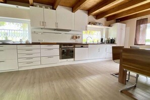 Eine moderne Küche mit weißen Schränken, einem eingebauten Backofen und einem Holzespeisetisch.