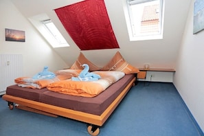 A room with a bed, a desk, and two windows. - Holiday apartment with 2 bedrooms (Borkum)