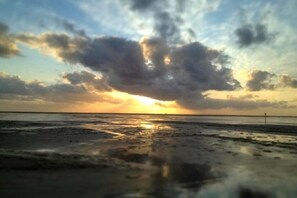 Een strand met een zonsondergang en wolken.