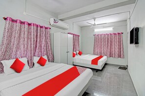 Habitación de hotel con dos camas, ventilador de techo, unidad de aire acondicionado y un espejo que refleja la habitación.