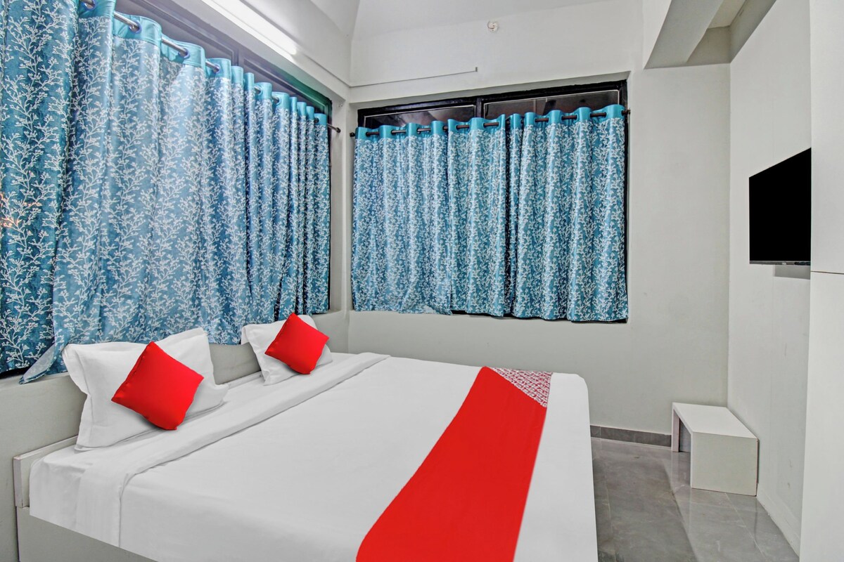 Una habitación de hotel moderna con una cama grande, dos almohadas rojas y un televisor en la pared.