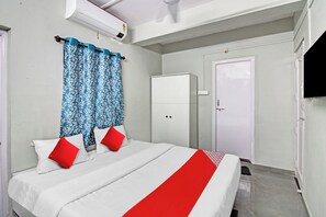 Un dormitorio con cama, armario, puerta y ventana con cortinas.