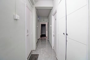 A corridor with white doors, a vent, and a tiled floor. - Hotel O Moonlight Inn (Nagpur)