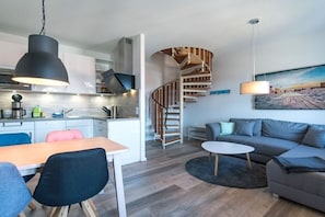 A modern interior with a kitchen, dining area, and living space, featuring a spiral staircase and a painting on the wall. - Holiday apartment with 1 bedroom (Borkum)