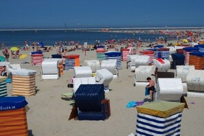 Ein Strand mit vielen Liegestühlen und Sonnenschirmen, von denen einige Nummern tragen.