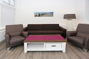 Une pièce avec un canapé marron, une table basse blanche et un lampadaire.