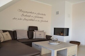 A modern living room with a sofa, a coffee table, and a flat-screen TV mounted on the wall. - Holiday apartment with 2 bedrooms (Borkum)