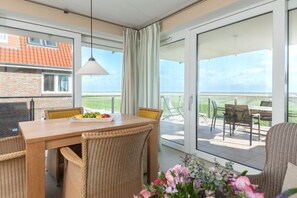 A balcony with a table and chairs, a view of the sky, and a building with a red roof in the background. - Holiday apartment in Juist with sauna (Juist)