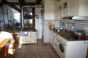 A kitchen with a stove, sink, and a dining area with a table and chairs. - Holiday home in Büschow with swimming pool (Büschow)