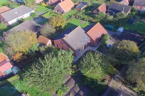 An aerial view of a residential area with houses, green lawns, and trees. - I Family Smid Pilsum (Pilsum)
