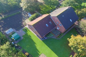 An aerial view of a two-story house with a sloped roof, a fenced yard, and a small garden area. - I Family Smid Pilsum (Pilsum)