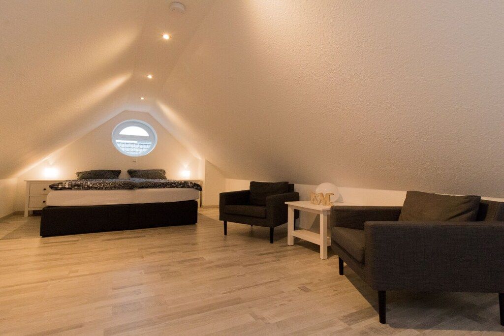 A bedroom with a bed, a nightstand, a chair, a sofa, and a small table.