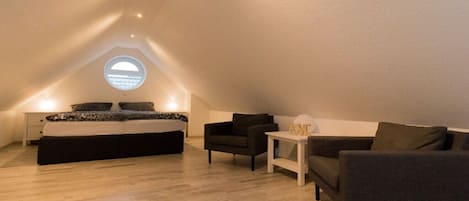 Ein Schlafzimmer mit Bett, Nachttisch, Stuhl, Sofa und einem kleinen Tisch.