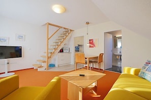 A compact living space with a staircase, a dining area, and a TV. - Seestern No. 2 Apartment House Seestern (Norderney)