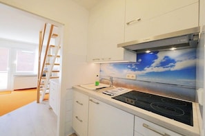 A kitchen with white cabinets, a Bosch range hood, and a window with a view of the sky. - Seestern No. 2 Apartment House Seestern (Norderney)