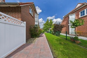 A residential street with brick houses, a white fence, and a paved walkway. - Holiday home in Dornum with Wi-Fi and gym (Dornum)