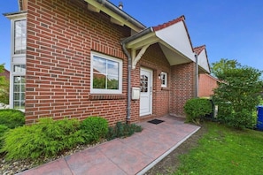 A brick house with a front porch, a door, and a window. - Holiday home in Dornum with Wi-Fi and gym (Dornum)