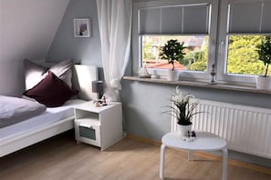A bedroom with a bed, bedside table, nightstand, window with blinds, and a potted plant. - Holiday home in Tossens with swimming pool (Tossens)