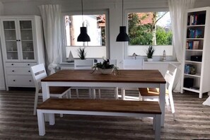 A dining area with a wooden table and chairs, a cabinet with glass doors, and a bookshelf. - Holiday home in Tossens with swimming pool (Tossens)
