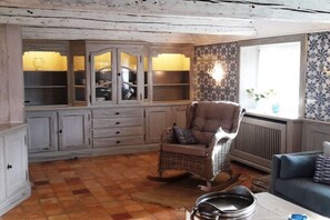 A room with a rocking chair, a blue sofa, and a cabinet with glass doors. - Old Beach Warden's Office (List)