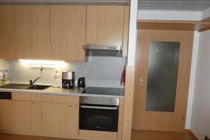 A kitchen with wooden cabinets, a stainless steel range hood, a built-in oven, and a sink. - Neptune House Iderhoff Norderney (Norderney)
