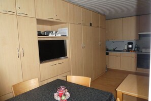A compact room with a television, a small table with a tray, and a kitchenette area. - Neptune House Iderhoff Norderney (Norderney)
