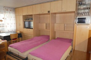 A compact room with two beds, a desk, and a microwave. - Neptune House Iderhoff Norderney (Norderney)