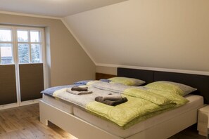 Ein Schlafzimmer mit einem Bett, einem Nachttisch, einem Fenster und Blick ins Freie.