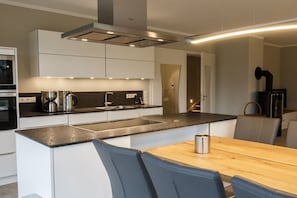 A modern kitchen with a central island, stainless steel appliances, and a dining area with a wooden table and chairs. - Holiday apartment with 3 bedrooms (Born a. Darß)