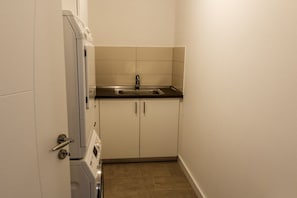 Cozinha compacta com forno embutido, pia e armário.